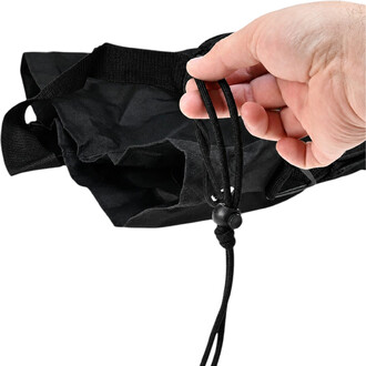 Sac à ballons noir en tissu, fermeture par corde de serrage avec bloqueur, main tenant les cordons.