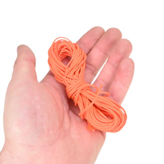 Main tenant une pelote de ficelle orange fine et enroulée, prête à être utilisée pour diabolo.