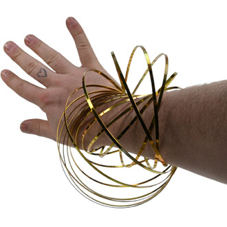 Sculpture cinétique anodisée dorée composée de fines bandes métalliques spiralées entourant le poignet et la main.