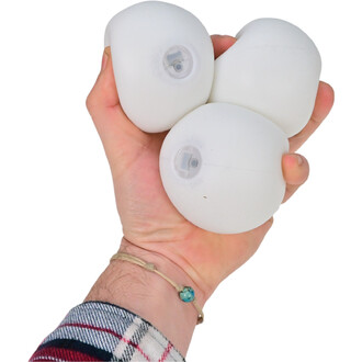 Image d'un set de trois balles LED Lumi Pro de la marque Threeworlds, tenues dans une main. Les balles sont blanches et présentent un dispositif lumineux à l'intérieur, visible par un petit trou. La main est ornée d'un bracelet en cordon, et un motif de c