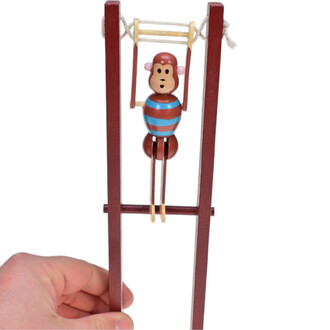 Singe en bois acrobate suspendu à des barres, vêtu d'un maillot rayé bleu et marron, avec une expression surprenante, tenu par une main. Les barres sont en bois avec une finition marron.