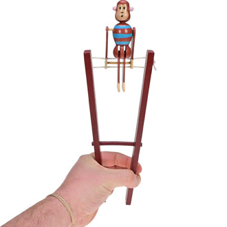 Mignon singe acrobate en bois, assis sur une barre, avec des rayures bleues et rouges, tenu par une main. La barre est en bois marron avec un cordon.