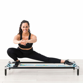 Femme effectuant un exercice de fente latérale sur la structure autoportante SlackGYM avec deux slacklines élastiques, illustrant l'amélioration de l'équilibre et de la flexibilité.