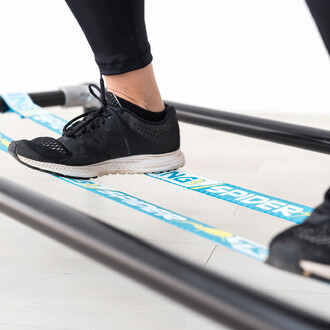 Gros plan sur les pieds d'une personne utilisant la slackline élastique de la structure autoportante SlackGYM, montrant l'engagement des muscles pour maintenir l'équilibre.