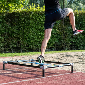 Homme effectuant un exercice de saut sur une structure autoportante SlackGYM en extérieur, montrant l'amélioration de l'équilibre, de la coordination et de la force musculaire.