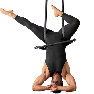 Artista circense de collant preto, suspenso de cabeça para baixo por fitas aéreas, segurando uma corda inteligente preta equilibrada nos quadris.