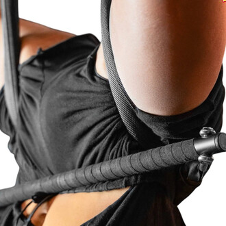 Imagem em close-up de uma corda de pular Smart Rope preta enrolada na cintura de uma pessoa vestindo uma camiseta preta, mostrando a textura da alça e o cabo da corda de pular conectada.