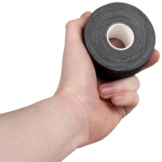 Ruban adhésif noir enroulé, tenu dans une main, avec une ouverture centrale visible.