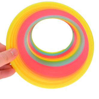 Arc-en-ciel géant en plastique souple, présenté en plusieurs couleurs vives, tenant dans une main. Il a une forme circulaire avec un trou au centre, comportant des bandes concentriques de coloris jaune, rose, vert et bleu.