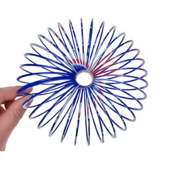 Mains tenant un objet à ressort coloré, en forme de spirale, avec des motifs bleu, rouge et blanc. L'objet est ouvert en forme de fleur, révélant un trou central.