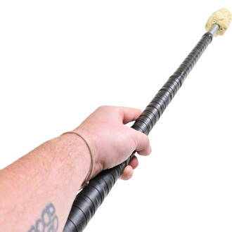 Main tenant un staff de jonglerie Contact ISIS de 150 cm, avec une texture noire et une tête en mousse. Le fond est blanc, mettant en valeur l'outil de jonglerie.