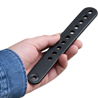 Barre métallique noire perforée avec une rangée de trous ronds, tenue dans une main – accessoire de jonglerie.