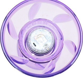 Vue en plongée d'un taibolo lumineux de couleur violet transparent, révélant la base avec des composants électroniques et un port USB pour la recharge. Les motifs de la coupelle sont visibles à travers le matériau.