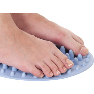 Description des pieds posés sur un tapis de massage en silicone bleu, avec des picots sur toute la surface.