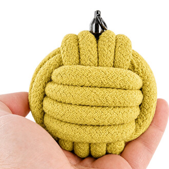 Der Kopf der Yellow Monkey Fist Bolas besteht aus geflochtenem Seil, ist kugelförmig und kompakt, wird zwischen den Fingern gehalten und hat oben eine Metallkappe und eine Befestigungsschlaufe.