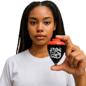 Une personne tenant une toupie Saturn Extrême (fixe) avec un corps noir et un sommet rouge. La toupie présente des graffiti blancs avec le mot SATURNO et XTRÊME dessus. La personne porte un t-shirt blanc et a les cheveux crépus et longs.
