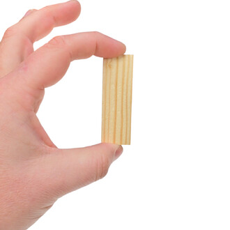 Bloc de jonglerie en bois, tenu par une main, avec des rainures sur la surface et un fond blanc.