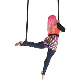 Trapèze Prodigy Polysafe – artiste suspendue par des sangles noires, vêtue d’un haut orange et de leggings rayés multicolores, cheveux roses, réalisant une figure aérienne sur le trapèze contre un fond blanc.