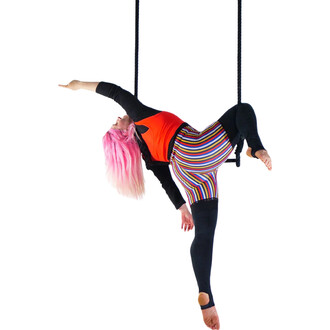 Airtiste exécutant une figure acrobatique sur un trapèze classique en coton, avec des vêtements colorés, incluant un top rouge et des leggings à rayures, suspendue par des cordes.