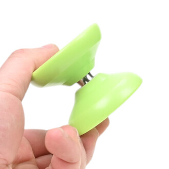 Gros plan d'un yoyo Skyva vert lime tenu entre le pouce et l'index sur fond blanc.