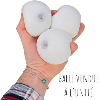 Quatre balles lumineuses blanches LUMI-PRO tenues dans une main, chacune avec une petite fenêtre LED; bracelet turquoise au poignet et texte BALLE VENDUE À L’UNITÉ sur l’image.