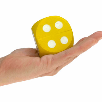 Yellow die placed in one hand to get an idea of the scale of a die.