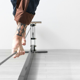 Image montrant un gros plan sur les pieds d'une personne en équilibre sur un fil d'acier. La structure du fil d'équilibre est visible à l'arrière-plan. L'image met en avant la précision et la stabilité requises pour marcher sur le fil.