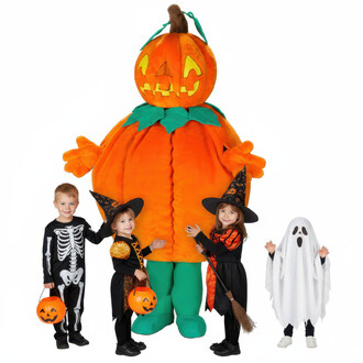 Mascotte Citrouille Maléfique entourée de trois enfants déguisés pour Halloween. Un garçon en costume de squelette, une fille en sorcière avec un chapeau noir, et une petite fille vêtue d'un drap de fantôme. La mascotte est grande, orange, avec un grand s