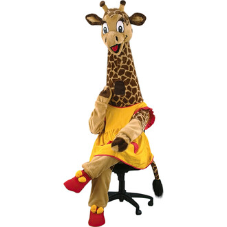 Mascotte girafe en costume, assise sur une chaise noire, portant une robe jaune avec un col rouge, des gants beige et des chaussures rouges, faisant un geste de la main. La tête de la mascotte est ornée d'une peau de girafe et elle a un sourire amical.