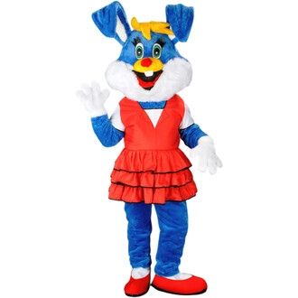 Mascotte lapine cartoon avec un costume bleu, une grande tête souriante, des oreilles de lapin, et une robe rouge à volants. Elle fait un geste de la main et porte des chaussures rouges.