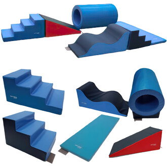 Kit Aventure composé de modules en mousse : un escalier à quatre marches, un plan incliné rouge et noir, un escalier à trois marches, deux tapis de jeu bleus, un tonneau bleu, et un module à double vagues noir et bleu. Tous les éléments sont recouverts de