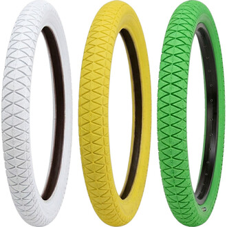 Tre pneumatici Qu-ax 20x1.95 allineati (bianchi, gialli e verdi) con cerchi neri a vista.