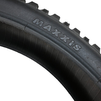 Pneu de vélo pour cross, mesurant 20x2.5, avec la marque MAXXIS visible sur le flanc. Le pneu présente un motif de bande de roulement profonde et des détails texturés sur sa surface.