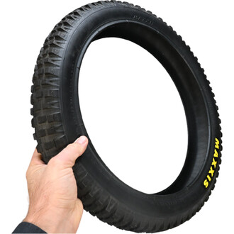 Pneu de 20x2.5 pour vélo tout terrain, avec un motif de bande de roulement agressif, tenu à la main. Le pneu est noir avec des inscriptions jaunes sur le flanc.