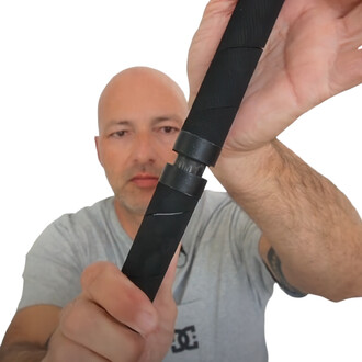 Homme tenant un tube carbone pliable Flowbonacci démontrant son mécanisme d'assemblage, sur fond blanc. Le tube est noir, avec des textures visibles, et l'homme est en t-shirt gris.